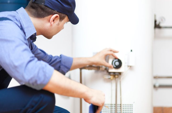 A technician checking the temperature regulator of a water heater
