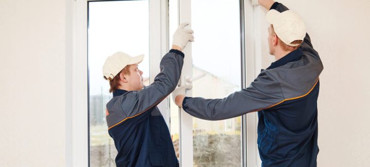 Two professional window installers carefully placing a frame for window replacement